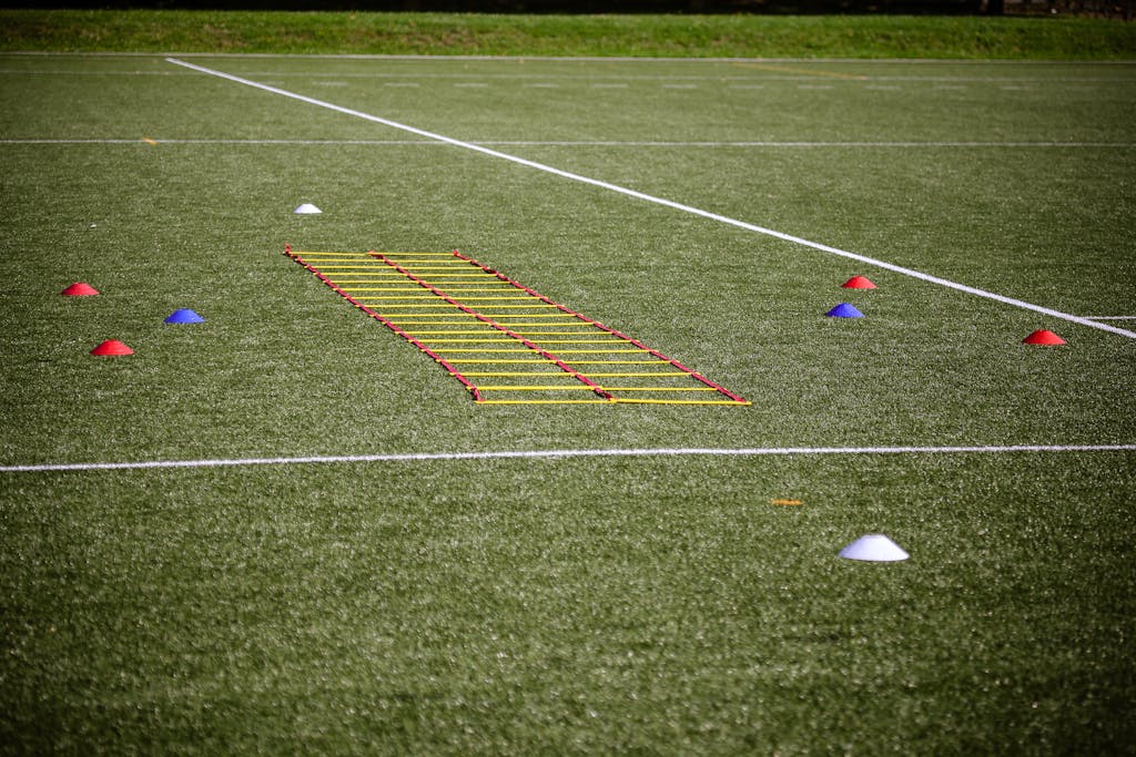 Agility ladder and marker cones set up on a grassy football field for training.
