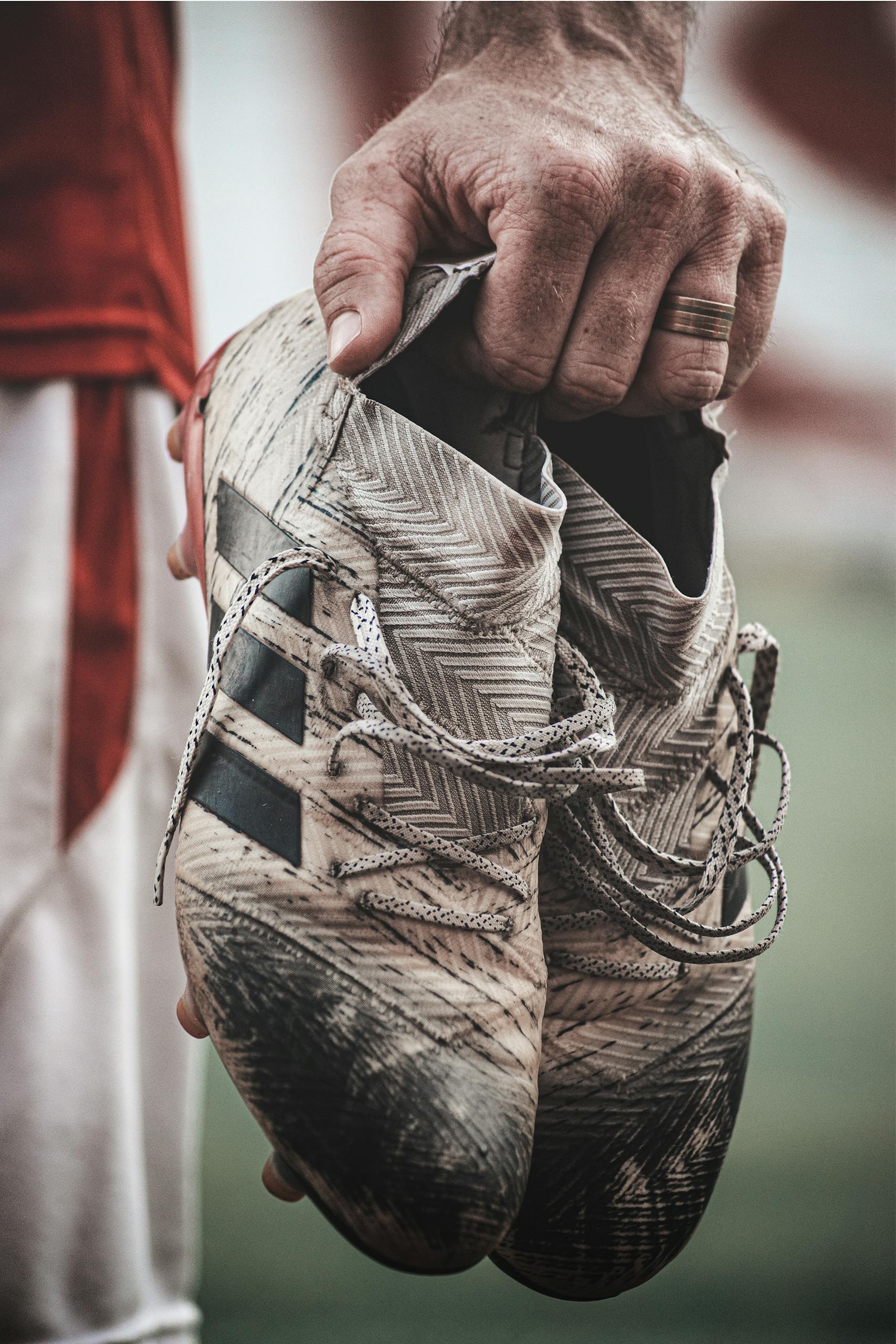 Detailed shot of a hand holding worn soccer cleats highlighting the sport's rugged nature.